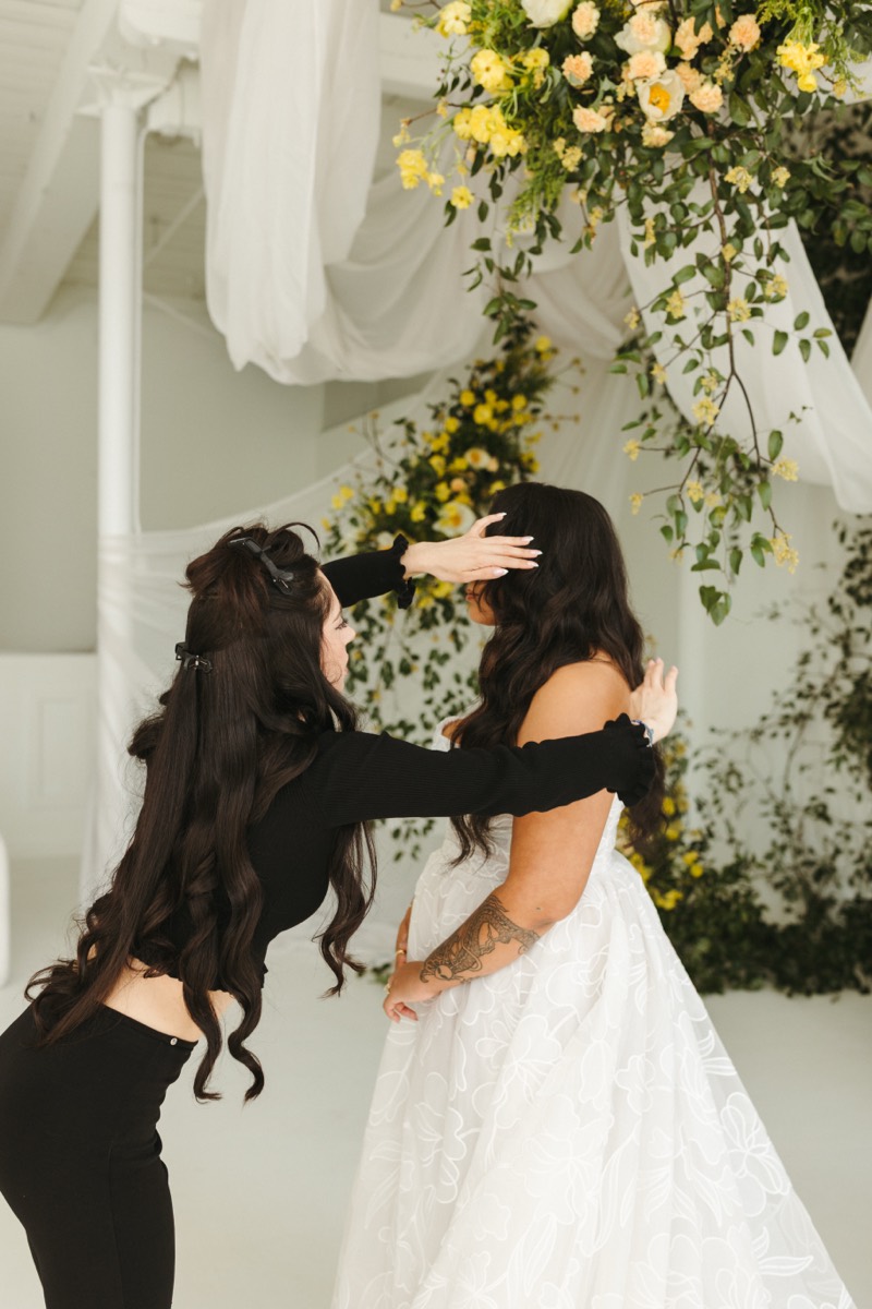 Bride and stylist beneath a floral ceremony installation